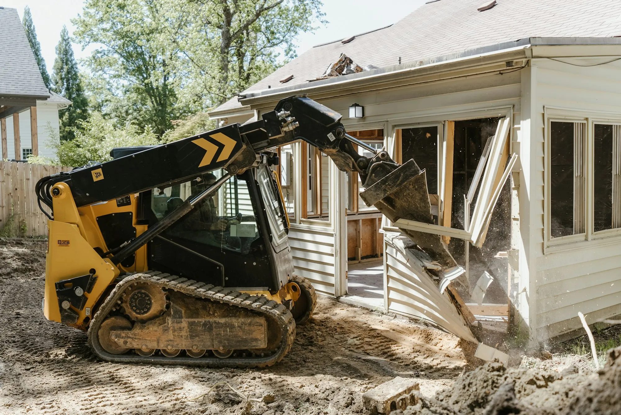 Track loader working beside a partly demolished house